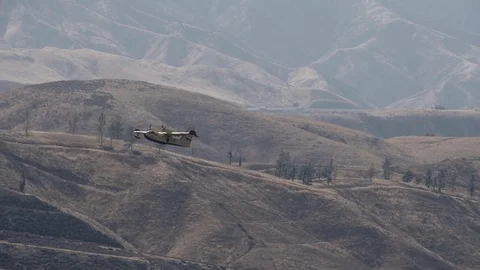 Super scooper long slow motion climbout in mountainous terrain Stock Footage 79862034