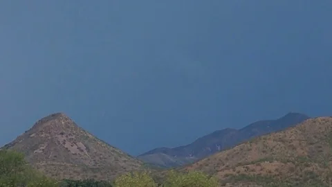 Super slomo daytime sheet lightning strike over desert mountains Stock Footage