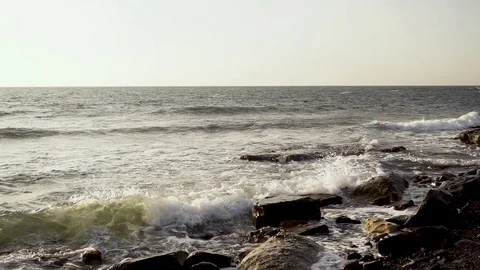 Super slow mo sea wave breaks about boulders Stock Footage 82457665