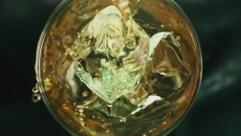 Super slow motion 1000fps top view on pouring beer on green ice cubes in rotate Stock Footage 255196821