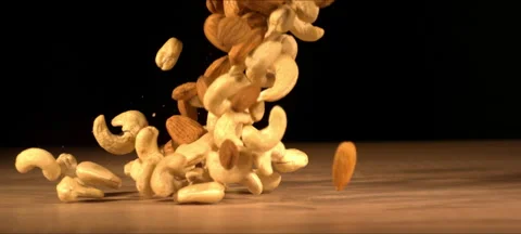 Super slow-motion of almonds and cashews fall on wooden table Stock Footage 323440112