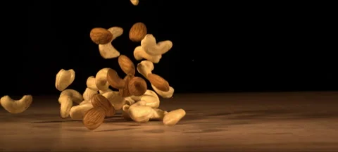 Super slow-motion of almonds and cashews fall on wooden table Stock Footage 323440127
