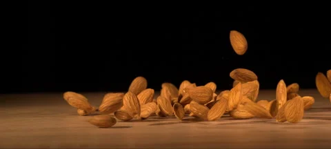 Super slow-motion of almonds fall on wooden table Stock Footage 323440164