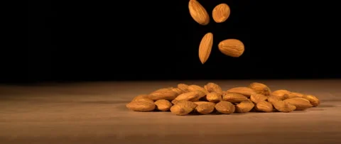 Super slow-motion of almonds fall on wooden table Stock Footage 323440185