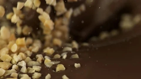 Super slow motion of blanched hazelnuts falling into molten chocolate. Stock Footage 141184403