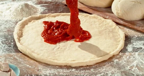 Super slow motion close-up of rich tomato sauce being poured onto pizza dough. Stock Footage 328827548