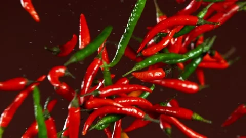 Super slow motion of coloured chilli peppers in collision, black background Stock Footage 132508187