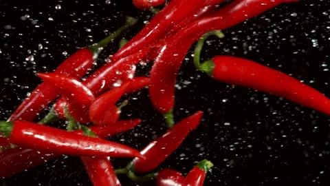Super slow motion of coloured chilli peppers in collision, black background. Stock Footage 136782050