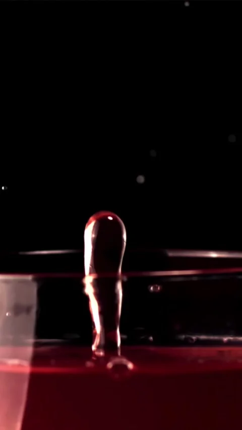 Super slow motion drop falls into a glass of wine with splashes. Filmed on a Stock Footage 335286810