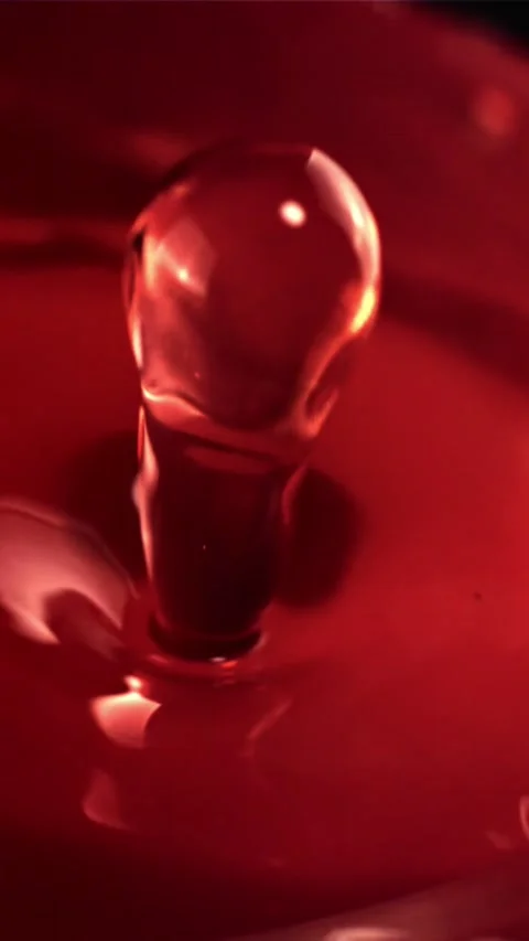 Super slow motion drop of wine with splashes falls into the glass. Filmed on a Stock Footage 335287890