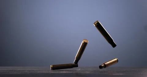 SUPER SLOW MOTION Empty machine gun shells falling on a ground against blue bg Stock Footage 152638741