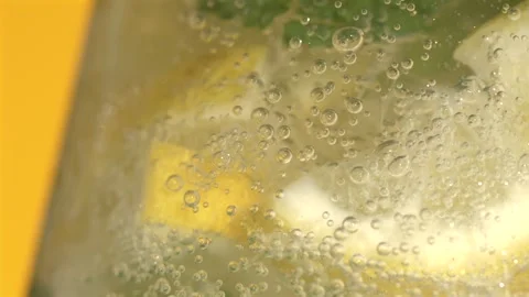 Super Slow Motion Energetic Display Of Foaming Drink Pouring Across Bright Lemon Stock Footage 327096676