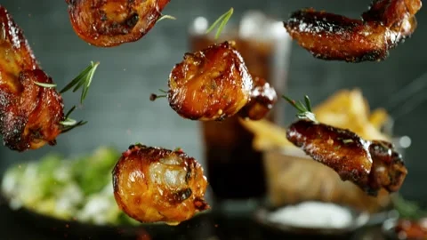 Super slow motion of falling chicken legs and wings on black background Stock Footage 238463541