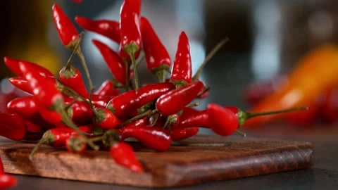 Super slow motion of falling chilli peppers on wooden board. Stock Footage 166968581