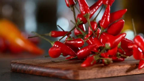 Super slow motion of falling chilli peppers on wooden board. Stock Footage 166969028