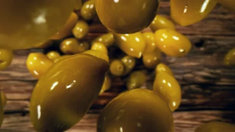 Super slow motion of falling green olives on wooden background. Stock Footage 149004243