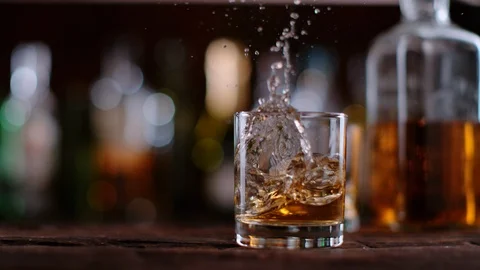 Super slow motion of falling ice cube into whiskey glass, 1000 fps Stock Footage