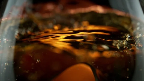 Super slow motion of falling ice cube into whiskey in super macro shot. Stock Footage 120953875