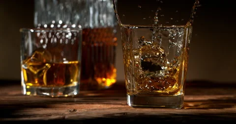 Super slow motion of falling ice cube into whiskey. Stock Footage 216930386