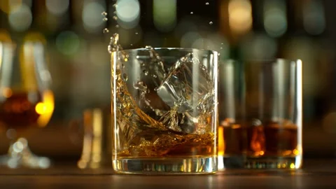 Super slow motion of falling ice cube into whiskey drink. Stock Footage 231029257