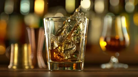 Super slow motion of falling ice cube into whiskey drink. Stock Footage 231029387