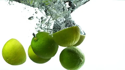 Super slow motion of falling lime pieces into splashing water with speed ramping Stock Footage 118977440