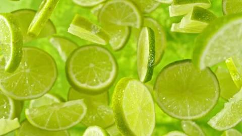 Super slow motion of falling lime slices on green background. Stock Footage 244400239