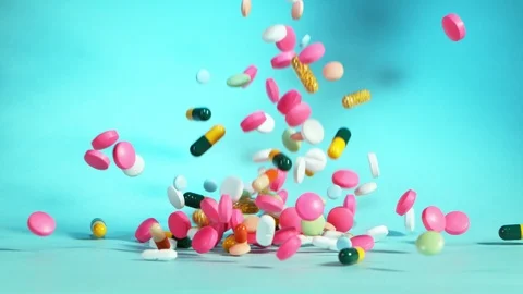 Super slow motion of falling mixed pills on blue background Stock Footage