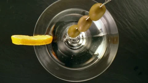 Super slow motion of falling olives into martini drink with camera motion Stock Footage 148690130