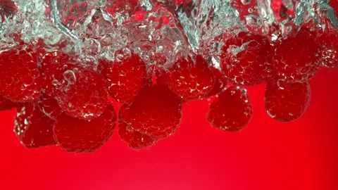 Super Slow Motion of Falling Raspberries Into Water on Red Background. Stock Footage 253743426