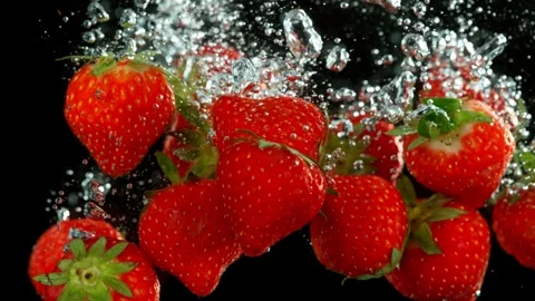 Super slow motion of falling strawberries into splashing water. Stock Footage 243023031
