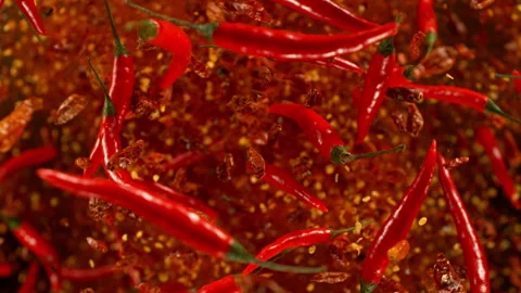 Super slow motion of flying and rotating red chilli peppers Stock Footage 240136723