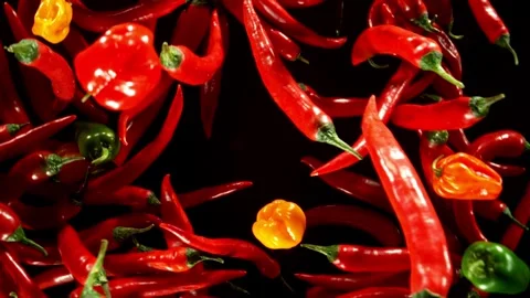 Super slow motion of flying and rotating colored chilli peppers. Stock Footage 282295776