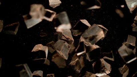 Super slow motion of flying group of raw chocolate pieces on black background Video stock 119738291