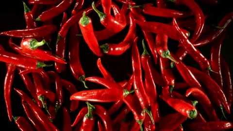 Super slow motion of flying red hot chilli peppers isolated on black. Stock Footage 286996674