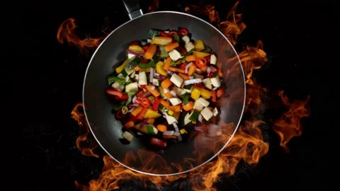 Super slow motion of flying sliced vegetable pieces from wok pan with fire Stock Footage 145675957