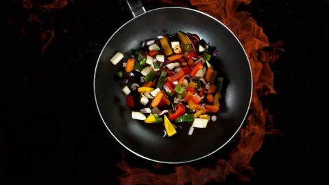 Super slow motion of flying sliced vegetable pieces from wok pan with fire Stock Footage 145676823