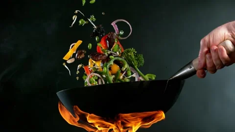 Super slow motion of flying sliced vegetable pieces from wok pan. Stock Footage 168833243