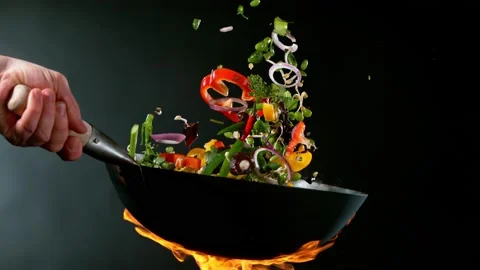 Super slow motion of flying sliced vegetable pieces from wok pan. Stock Footage 168833475