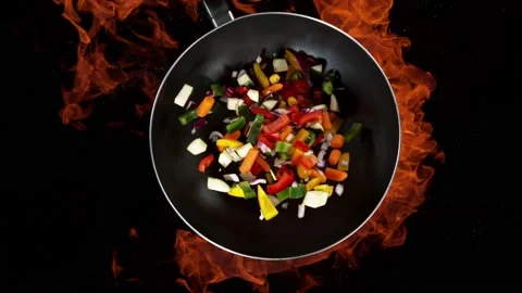 Super slow motion of flying sliced vegetable pieces from wok pan with fire Stock Footage 227312247