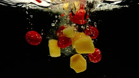 Super slow motion of fresh mango and pineapple falling into water on black Stock Footage 256300628