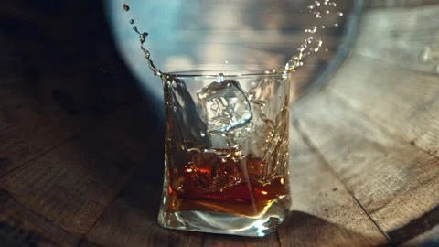 Super slow motion of ice cube falling into whisky glass. 動画素材 219000351