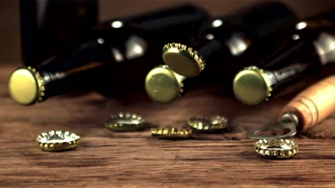 Super slow motion lids from beer bottles fall on the table. Filmed on a high Stock Footage 156440148