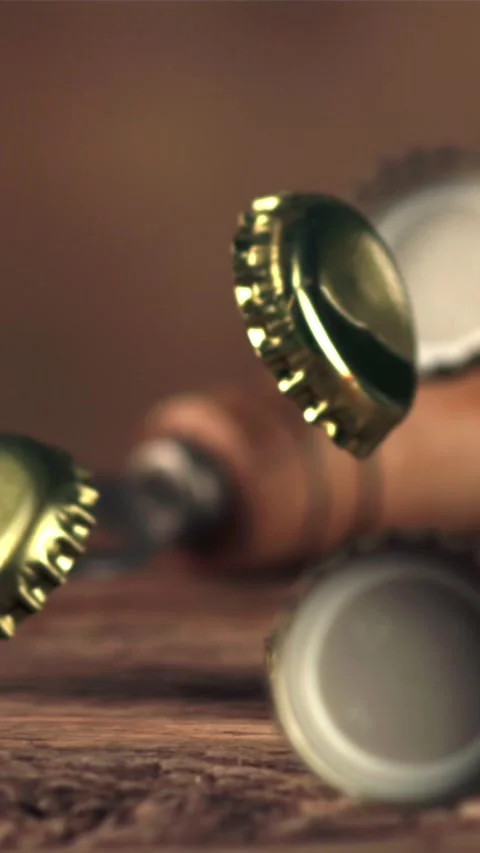Super slow motion lids from beer bottles fall on a wooden table. Filmed on a Stock Footage 335288192