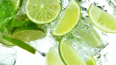 Super slow motion of lime slices falling into water with ice cubes on white. Stock Footage 133724964