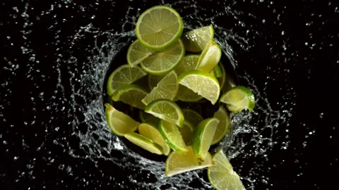 Super slow motion of lime slices rotating in water, black background Stock Footage 134489607