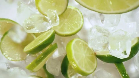 Super slow motion of lime slices falling with ice cubes on white background Stock Footage 149005041