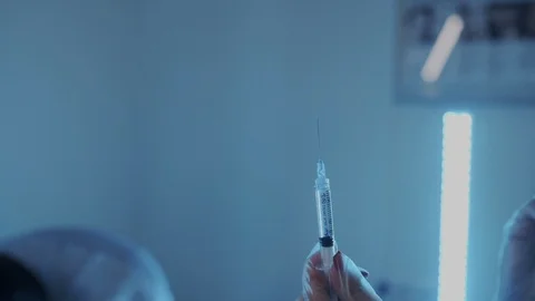 Super slow motion. The liquid spills out of the syringe. A woman's hand tries Stock Footage 114285302