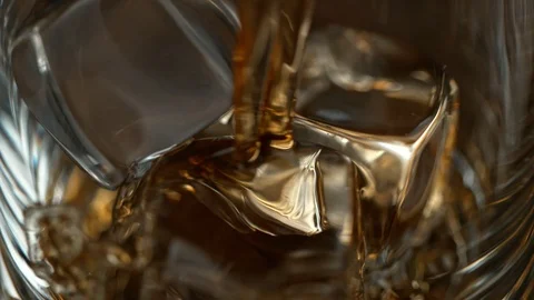 Super Slow Motion Macro Shot of Pouring Whiskey into Glass with Ice Cubes at Vidéo 121249967