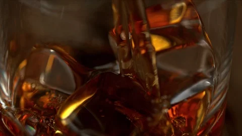 Super Slow Motion Macro Shot of Pouring Whiskey into Glass with Ice Cubes at Stock Footage 125305083